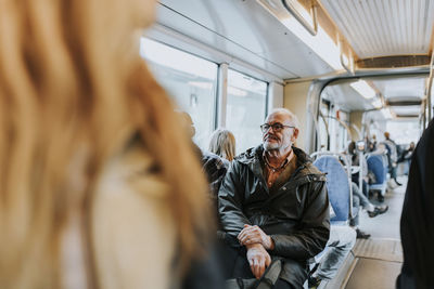 Contemplative male owner sitting in bus while traveling to work