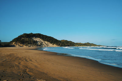 Scenic view of beach against clear blue sky