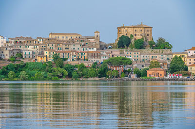 Buildings by river against sky in city