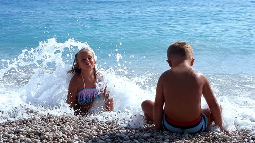 Siblings sitting on beach