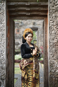 Portrait of young woman standing against wall