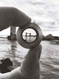 Close-up of hand holding camera against sky