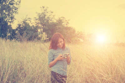 Woman on field against sky during sunset