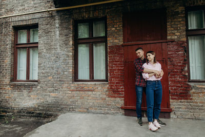 Young couple standing against brick wall