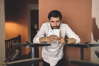 Male chef using smart phone in restaurant