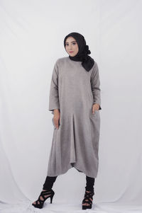 Portrait of young woman standing against white background