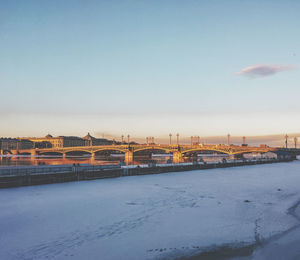 Bridge over river in city during winter against sky