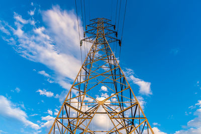 High voltage tower with electricity transmission power lines in sunset light.