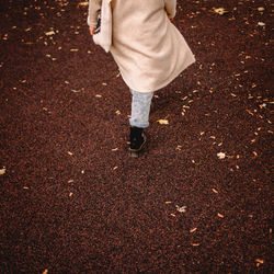 Back view of young woman walking in park during autumn