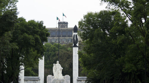 Statue in city against sky