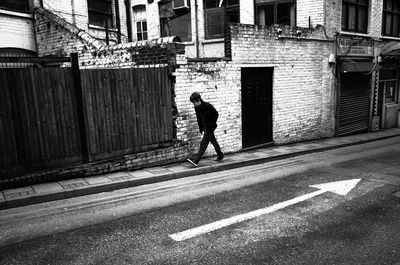 Full length of man walking on road against buildings in city