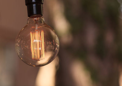 Close-up of lit light bulb against blurred background