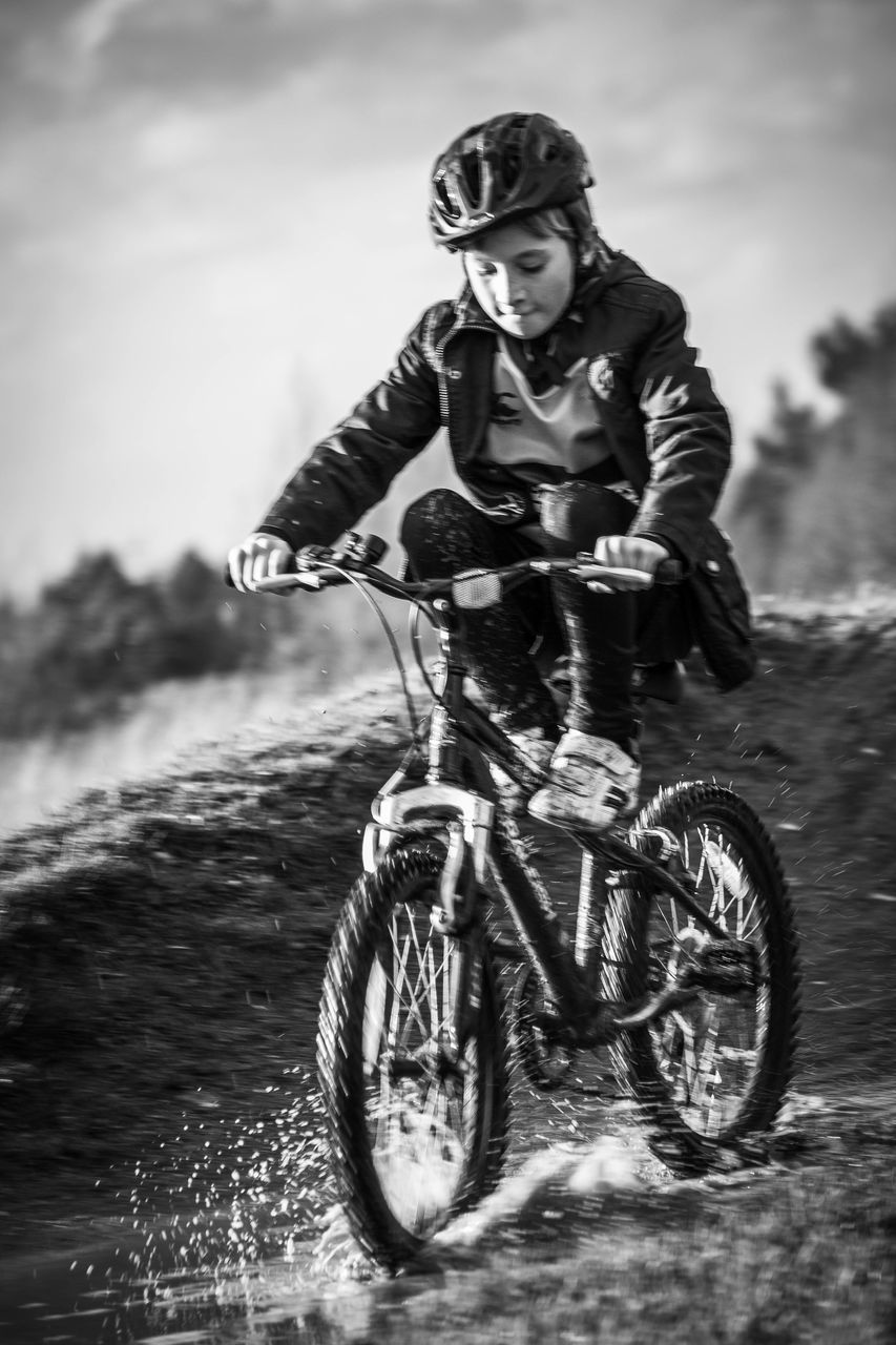 bicycle, mode of transport, transportation, land vehicle, sky, stationary, day, outdoors, travel, riding, cloud - sky, wheel, sunlight, nature, human representation, motorcycle, leisure activity, low angle view