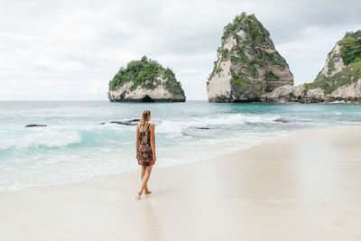 Woman standing on beach against sky