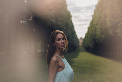 Portrait of young woman standing against sky during sunset