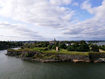 Scenic view of river by city against sky