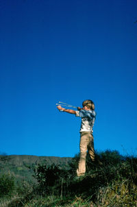 Full length of boy aiming catapult on sunny day