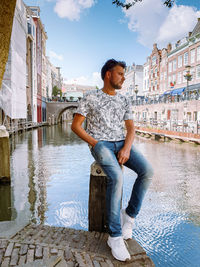 Woman standing by canal against buildings in city