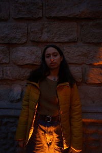 Portrait of young woman standing against wall