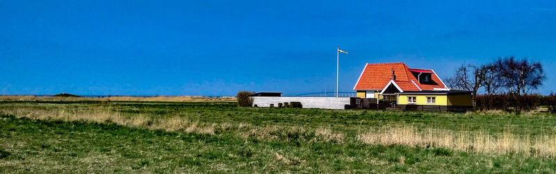 House on field against clear blue sky