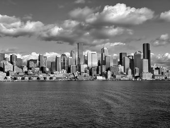 Sea by modern buildings against sky in city