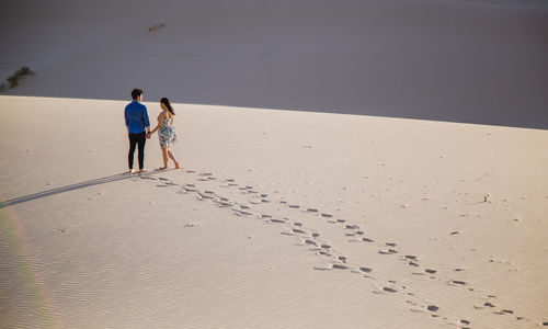 Rear view of people walking on beach