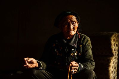 Man looking away while sitting in the dark