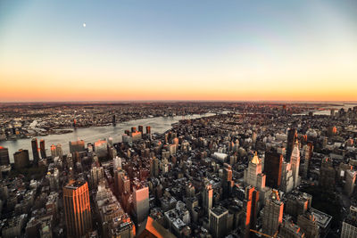 Aerial view of illuminated cityscape against sky during sunset