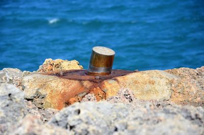 Close-up of rusty metal on rock by sea