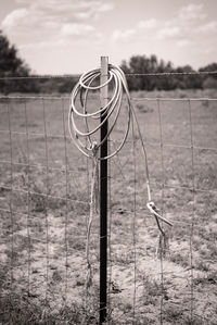 Metal fence on field against sky