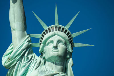 Low angle view of statue of liberty against blue sky