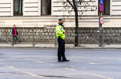 Side view of man with umbrella standing on road