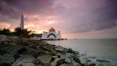 Panoramic view of sea and buildings against sky during sunset