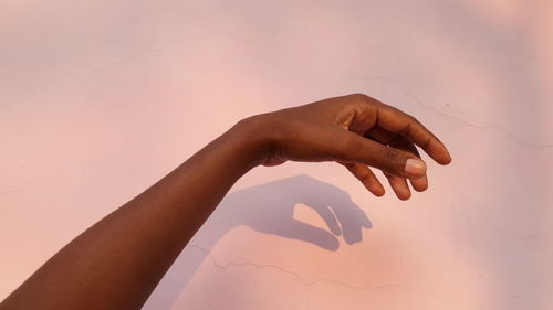 Close-up of hand against pink background 