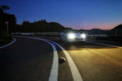 Illuminated road against clear sky at night