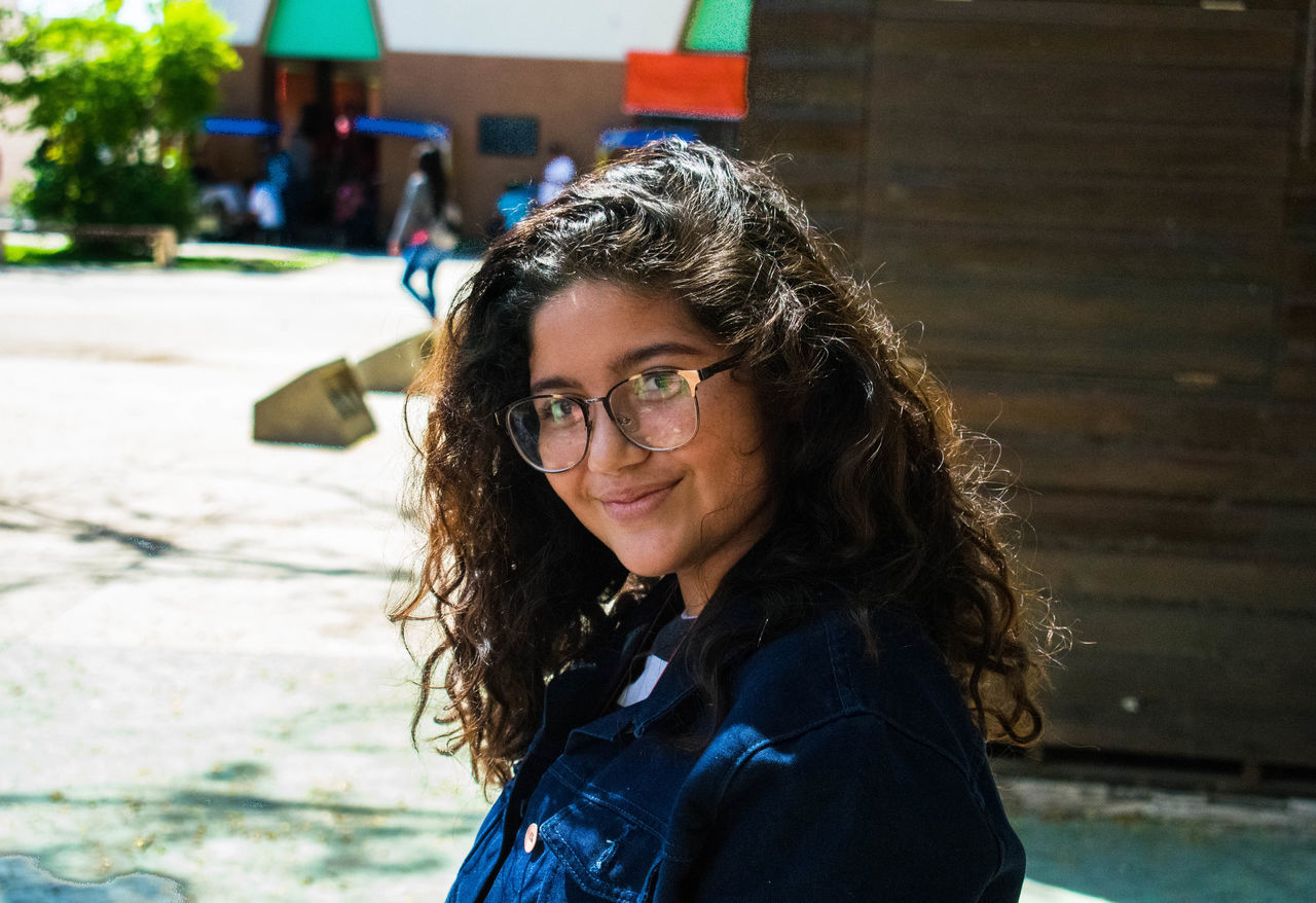 looking at camera, portrait, real people, smiling, one person, happiness, lifestyles, outdoors, architecture, day, eyeglasses, young women, young adult