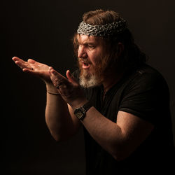 Midsection of man with arms raised against black background