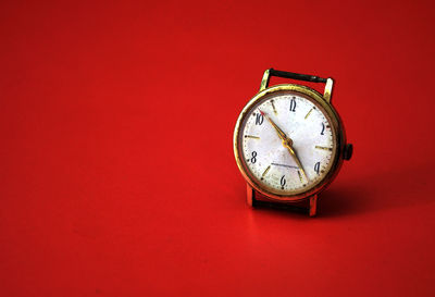 Close-up of antique clock against red background