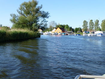 Scenic view of river by buildings against sky