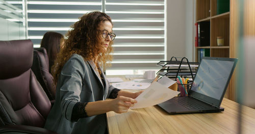 Collegues working in office one making phone calls other typing on laptop. 