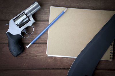 Directly above shot of pistol and knife with book on table