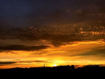 Silhouette landscape against dramatic sky during sunset