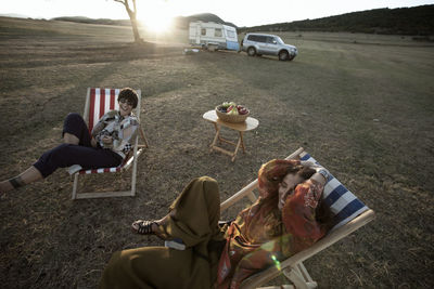 High angle view of happy friends sitting chairs at field