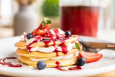Pancakes with cream, red syrup and served with blueberries and strawberries. breakfast at the cafe.