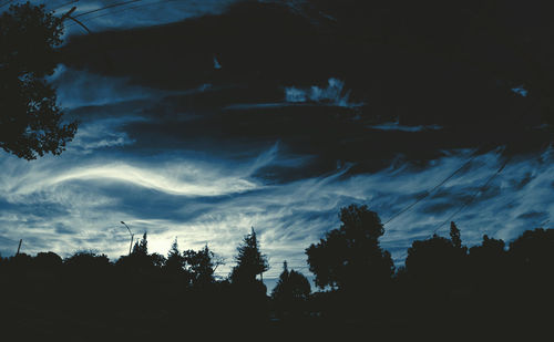 Low angle view of trees against cloudy sky