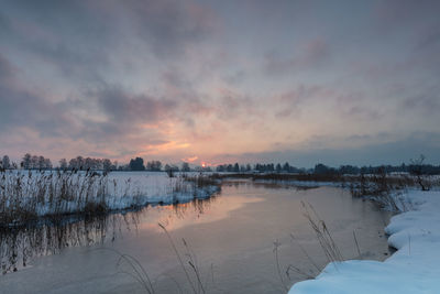 Scenic view of frozen lake against sky during sunset