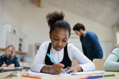 Concentrated student writing at desk in classroom