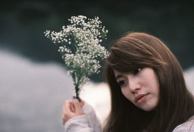 Thoughtful young woman holding flowers