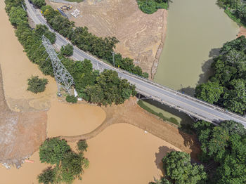 River flooding due to rain causes large mud next to a dam that prevents the rivers from meeting 