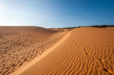 Sand dunes in desert against clear sky